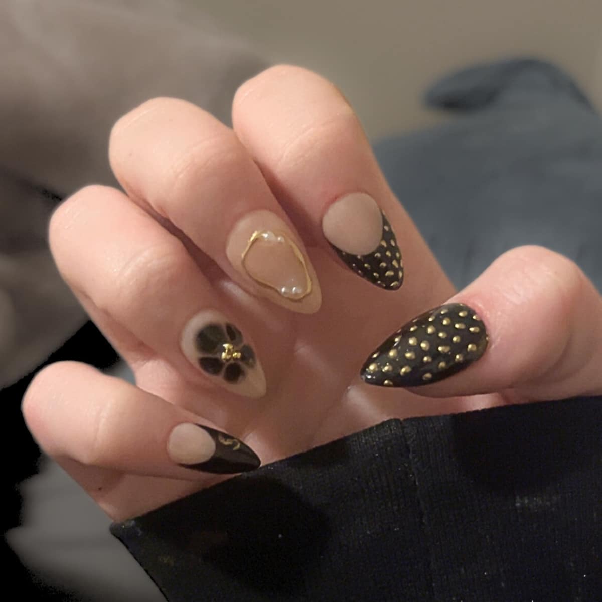 Almond set with black studded tips, a gold-outlined flower, and negative-space accents.