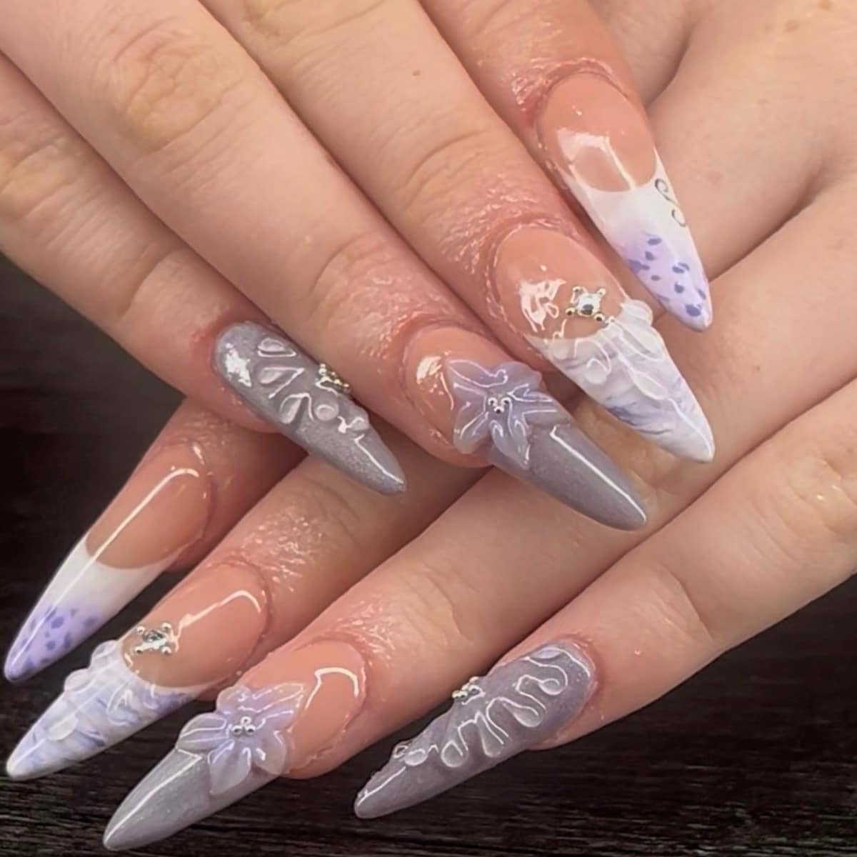 Long stiletto set in grey-lilac with sculpted 3D flowers, lace ruffles, and crystal accents.