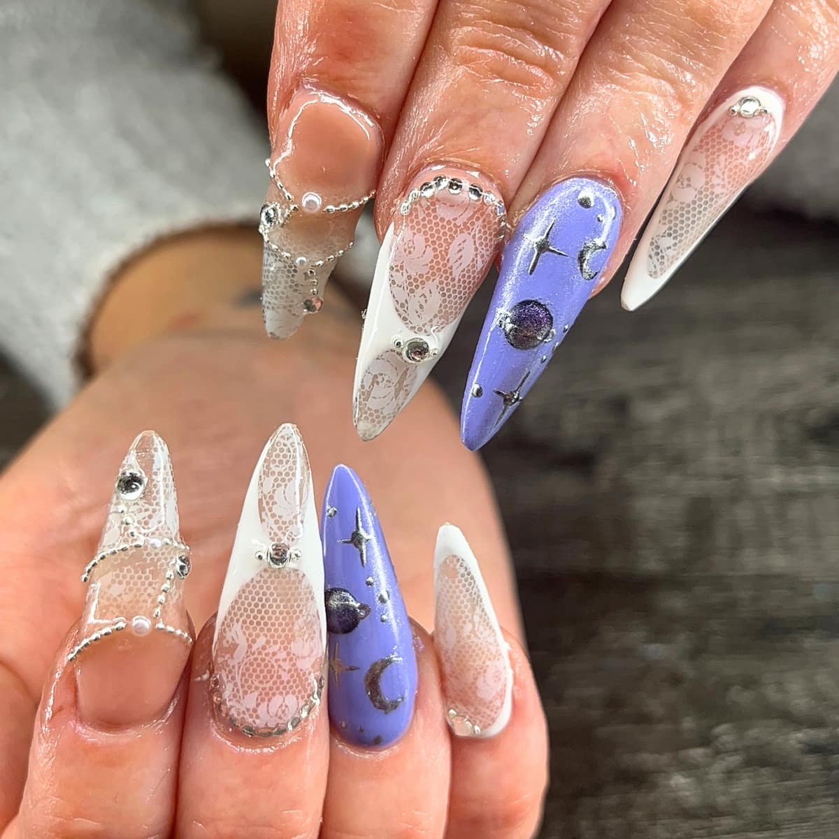 Long almond set pairing lilac moon-and-planet art with white lace tips and chain charms.
